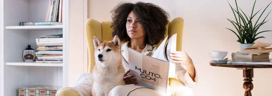 woman in armchair with dog reading magazine